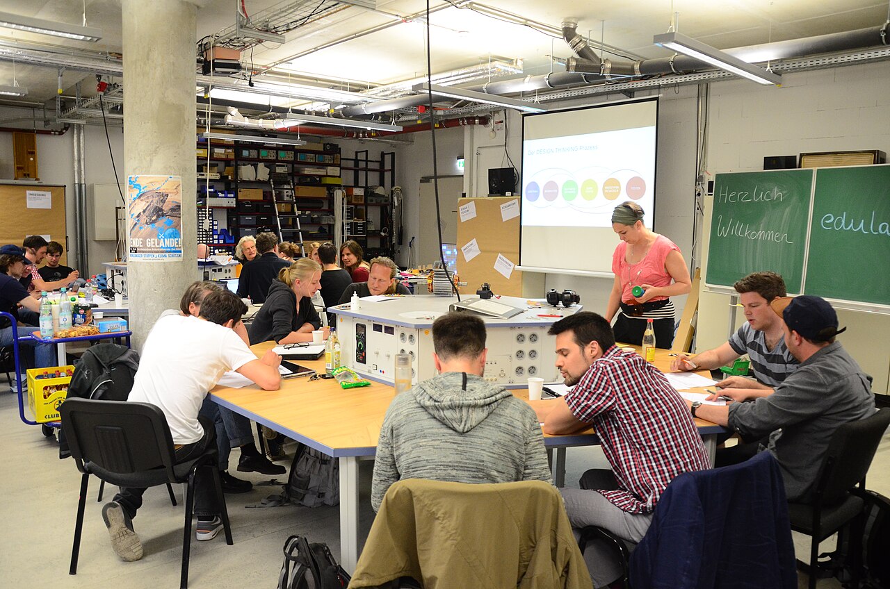 University students collaborating with laptops and lab equipment in a workshop setting